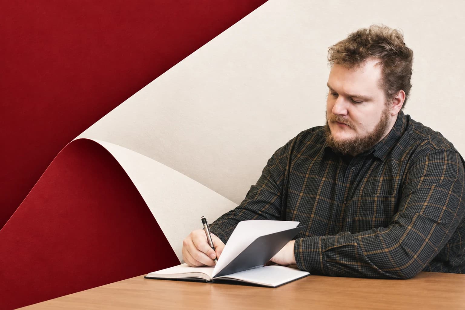 Photo illustration of a man writing in a notebook, with overlapping burgundy and cream paper folds.
